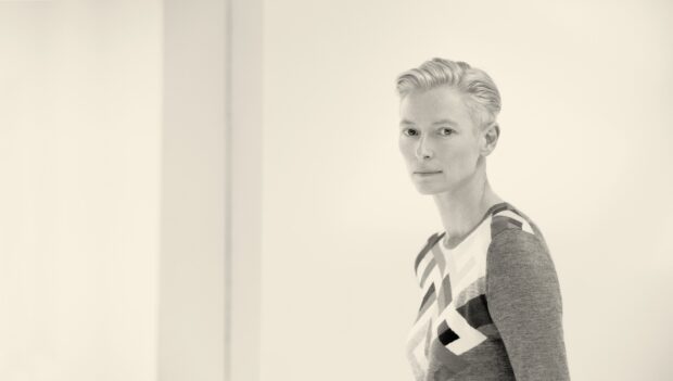 A monochrome photo of Tilda Swinton wearing a patterned top looking calmly at the camera, HD Desktop Wallpaper