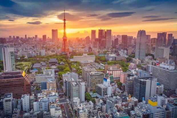 Tokyo Tower stands tall among city buildings at sunset with a glowing sky, HD Desktop Wallpaper