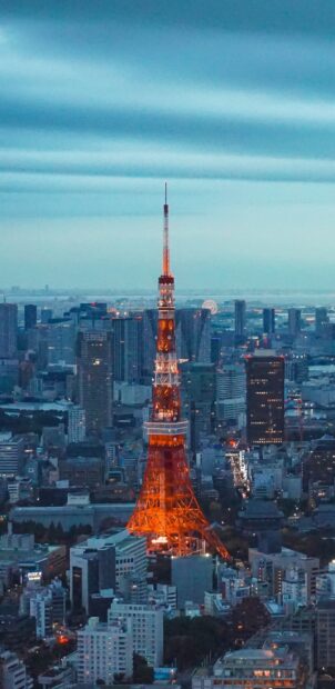 Tokyo Tower stands brightly lit among buildings in the evening cityscape, 2K Mobile Wallpaper