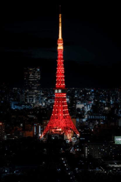The Tokyo Tower illuminated with bright red lights against the city skyline at night, 2K Desktop Wallpaper