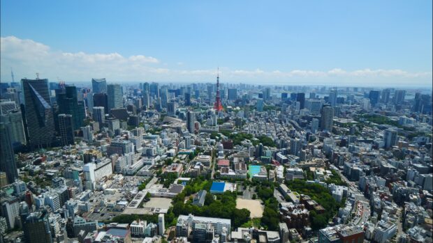 A clear view of Tokyo Tower surrounded by the city buildings on a sunny day, 4K Desktop Wallpaper