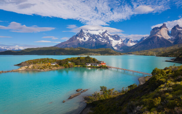 A turquoise lake with a connecting bridge and snow capped mountains in Torres Del Paine National Park, 2K Desktop Wallpaper