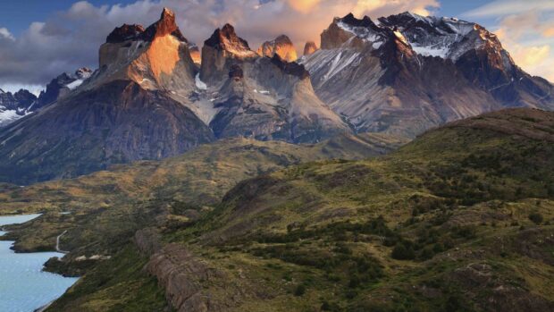 The Torres Del Paine National Park view shows sunrise lighting on rocky peaks and green hills, 4K Desktop Wallpaper