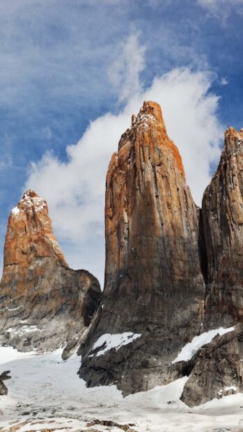 Tall orange rock formations rise above snow under the blue sky in Torres Del Paine National Park, HD Mobile Wallpaper