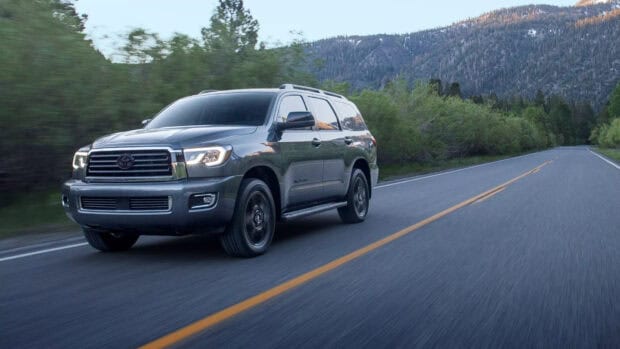 A gray Toyota Sequoia drives smoothly on a road surrounded by trees and mountain scenery, HD Desktop Wallpaper