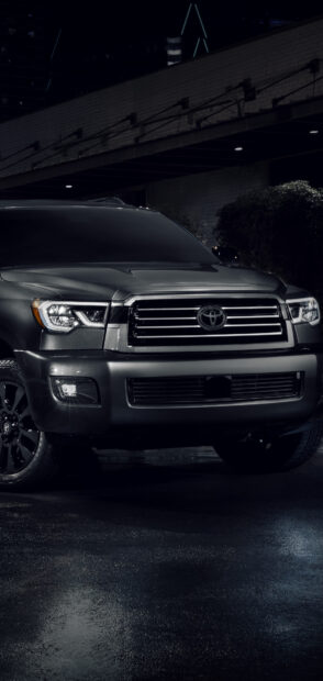 A dark gray Toyota Sequoia with headlights on parked under a building at night, HD Phone Wallpaper