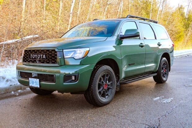 A green Toyota Sequoia is parked on a wet road with autumn trees in the background, HD Desktop Wallpaper