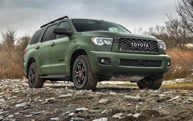 A green Toyota Sequoia is parked on rocky ground with bare trees in the background, HD Desktop Wallpaper