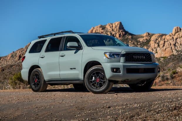 A Toyota Sequoia is parked on a dirt road with rocky mountains in the background, 2K Desktop Wallpaper
