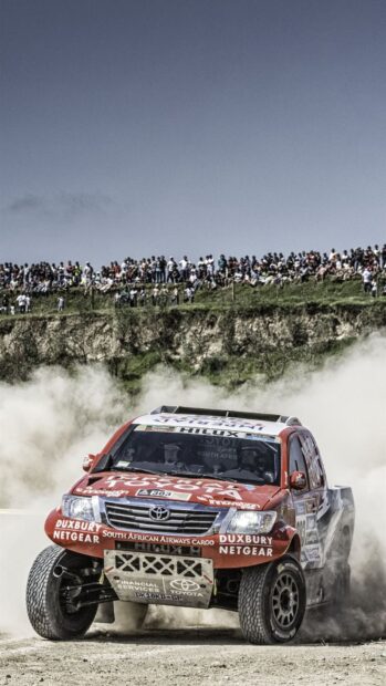 Toyota rally raid racing truck kicking up dust with crowd watching, HD Mobile Wallpaper