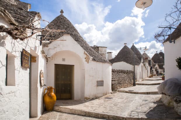 The Alberobello houses with conical roofs line the stone street under a bright sky, HD Desktop Wallpaper