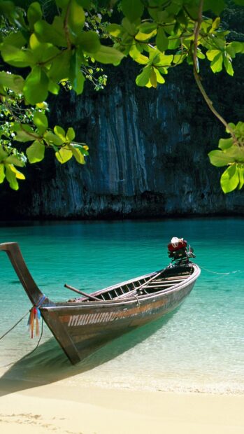 A traditional longtail boat floats near the shore with clear turquoise water in Phuket, HD Phone Wallpaper
