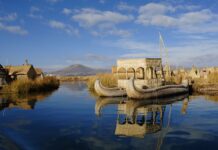 Traditional reed boat floating on peaceful water with mountains in the background in Peru Wallpapers, HD Desktop Wallpaper