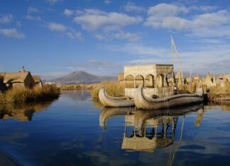 Traditional reed boat floating on peaceful water with mountains in the background in Peru Wallpapers, HD Desktop Wallpaper