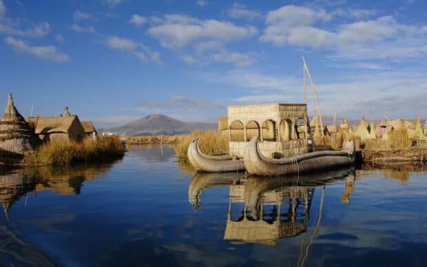 Traditional reed boat floating on peaceful water with mountains in the background in Peru Wallpapers, HD Desktop Wallpaper