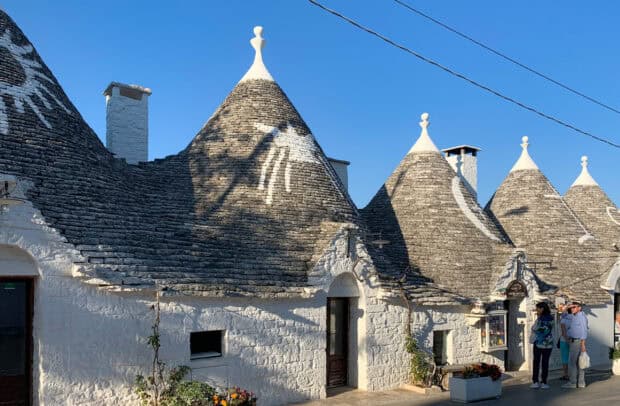 People exploring the unique trulli houses with conical roofs in Alberobello, 2K Desktop Wallpaper