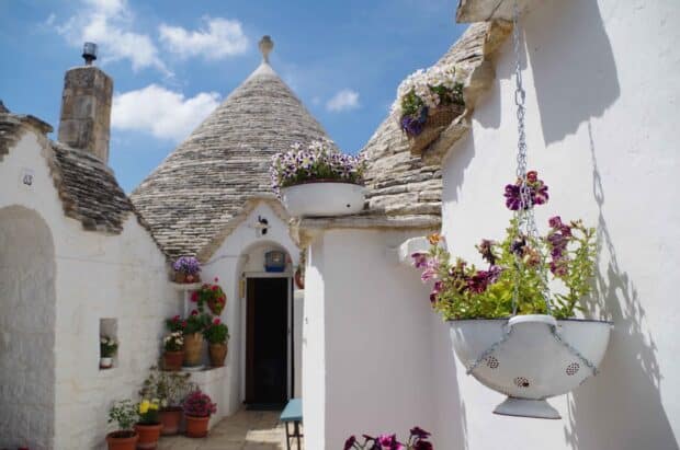 A hanging flower pot decorates the white wall of traditional trulli houses in Alberobello, HD Desktop Wallpaper