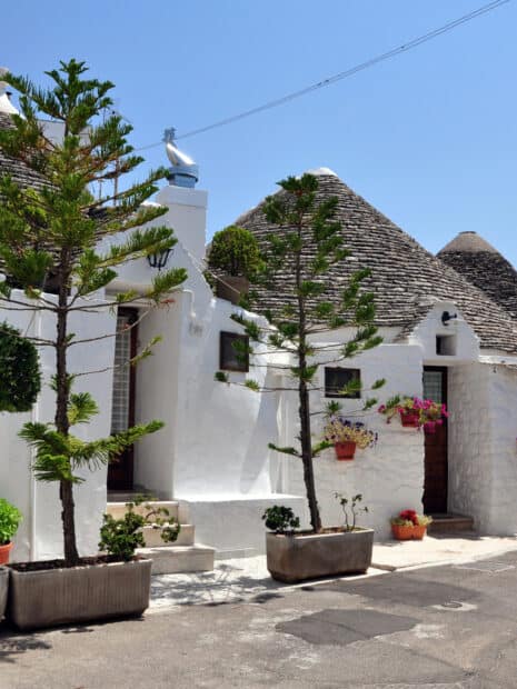 The unique Alberobello architecture features white houses with conical stone roofs under a clear blue sky, HD Mobile Wallpaper