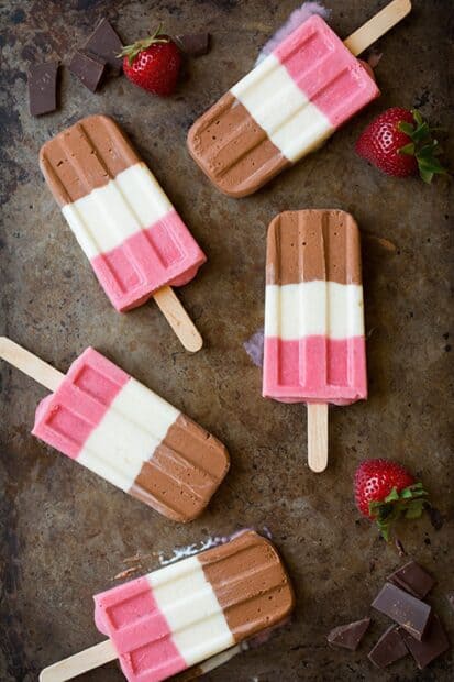 Tri color ice cream popsicles with strawberries on a rustic surface, 2K Mobile Wallpaper