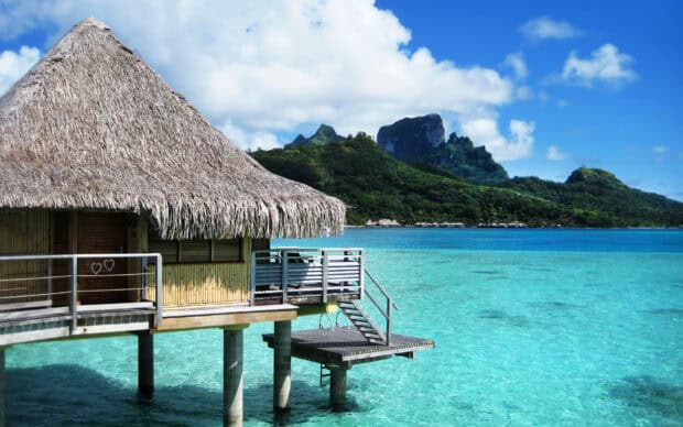 A tropical hut stands over clear blue water with lush green mountains in Palawan, HD Desktop Wallpaper