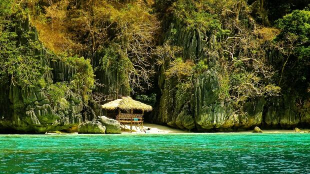 A tropical hut is nestled among limestone cliffs with lush trees in Palawan, HD Desktop Wallpaper