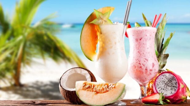 Two milkshakes with tropical fruits on a beach with ocean view, 2K Desktop Wallpaper
