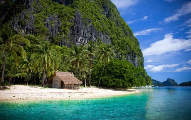 A tropical island in Palawan with clear turquoise waters and lush green trees surrounding the beach, 2K Desktop Wallpaper