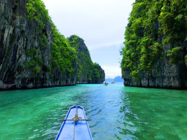 A blue boat approaches the stunning cliffs of Palawan with clear turquoise water, HD Desktop Wallpaper