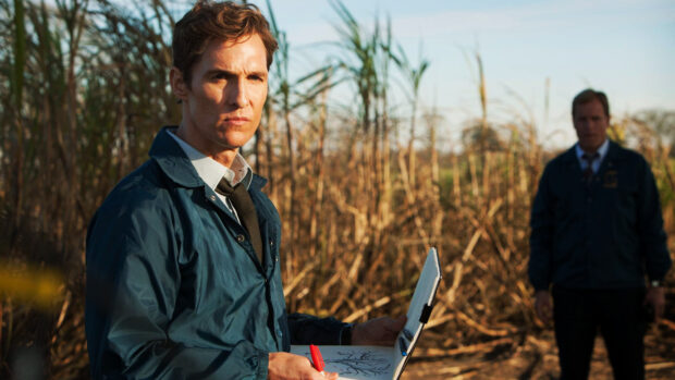 A detective studies a diagram while standing in a field with a colleague in the background, HD Desktop Wallpaper