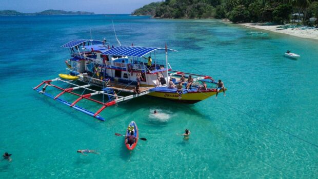 A boat with people enjoying the turquoise waters in Palawan coastline, HD Desktop Wallpaper