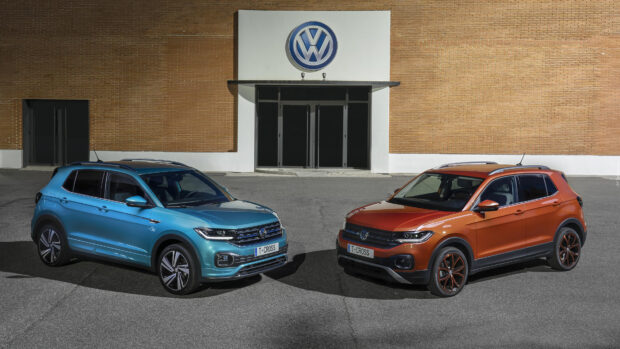 Two Volkswagen T Cross cars in blue and orange colors parked in front of a dealership with a large logo, 4K Desktop Wallpaper
