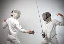 Two fencers in full gear face each other during a fencing match, HD Desktop Wallpaper