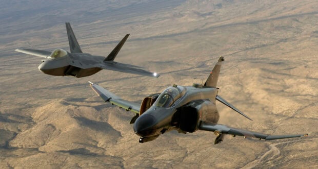Two jet fighters flying over a vast desert landscape during sunset, 2K Desktop Wallpaper