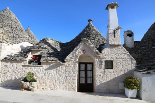 Traditional Alberobello architecture is shown with detailed stonework and a clear blue sky, HD Desktop Wallpaper