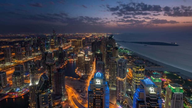 A vibrant cityscape of the United Arab Emirates with illuminated buildings and roads at dusk, 4K Desktop Wallpaper