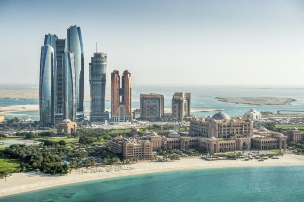 A panoramic view of United Arab Emirates skyline featuring tall skyscrapers and a coastal palace, 2K Desktop Wallpaper