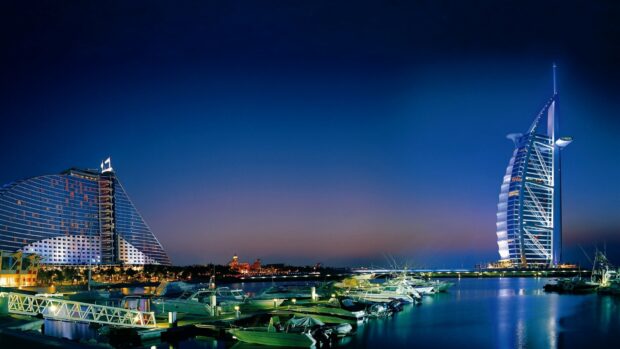 The United Arab Emirates showcases its stunning night skyline with iconic buildings and calm water, HD Desktop Wallpaper