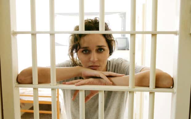 Valeria Golino looks thoughtfully through prison bars with a grey shirt, 2K Desktop Wallpaper