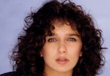Valeria Golino with curly hair wearing a black leather jacket against a plain background, 2K Mobile Wallpaper