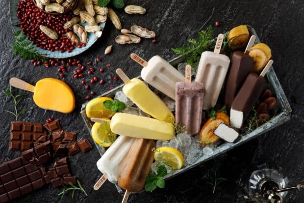 Different popsicle flavors are displayed on ice with fresh garnishes, HD Desktop Wallpaper