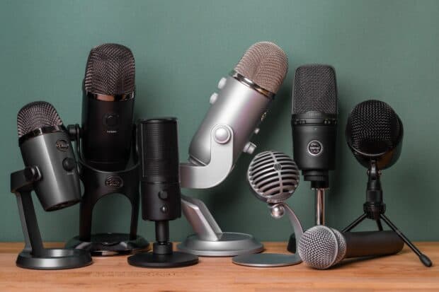 A collection of different microphones arranged neatly on a table for recording or broadcasting purposes, HD Desktop Wallpaper