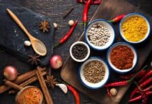 A wooden spoon with ground seasoning surrounded by assorted whole spices and red chili peppers, HD Desktop Wallpaper