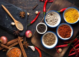 A wooden spoon with ground seasoning surrounded by assorted whole spices and red chili peppers, HD Desktop Wallpaper