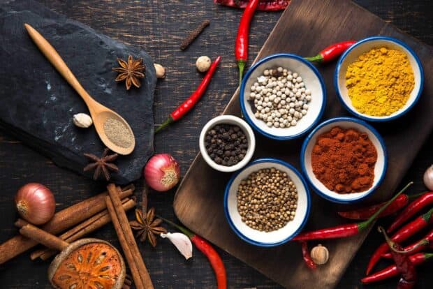 A wooden spoon with ground seasoning surrounded by assorted whole spices and red chili peppers, HD Desktop Wallpaper