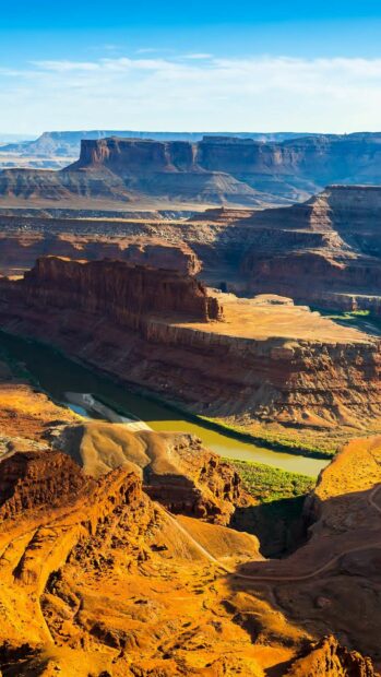 The Grand Canyon landscape features a winding river flowing through rocky terrain at sunset