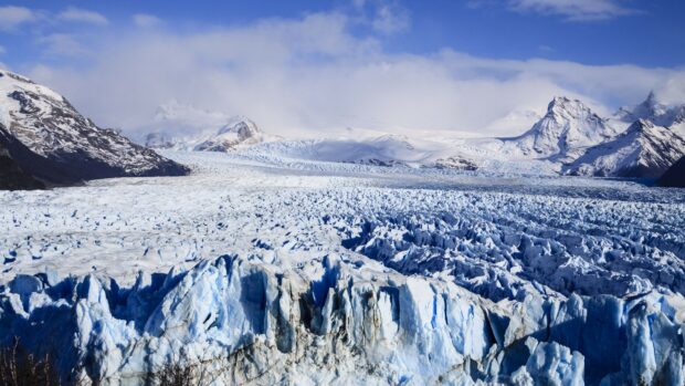 The glacier flows between the snowy mountains under a bright blue sky, 4K Desktop Wallpaper