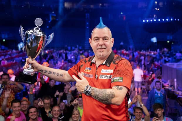 A darts player with blue mohawk holds a trophy while fans cheer at a darts event, 2K Desktop Wallpaper
