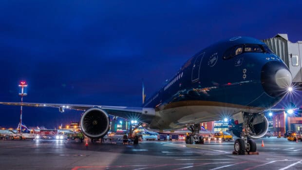 A Vietnam Airlines airplane is parked at the airport with lights glowing in the evening, HD Desktop Wallpaper