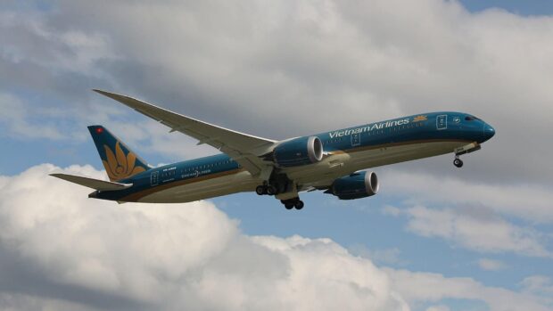 A Vietnam Airlines airplane flies through a partly cloudy blue sky in this aviation scene, HD Desktop Wallpaper