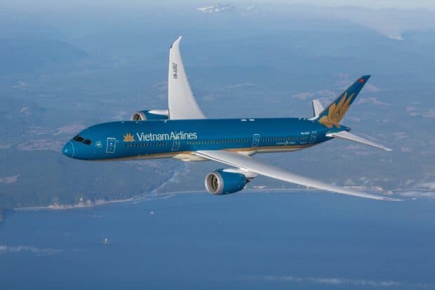 A Vietnam Airlines plane flies over a landscape with mountains and sea, HD Desktop Wallpaper